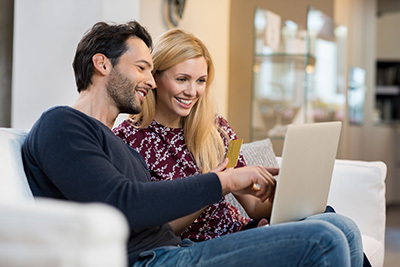Couple smiling on couch while online shopping